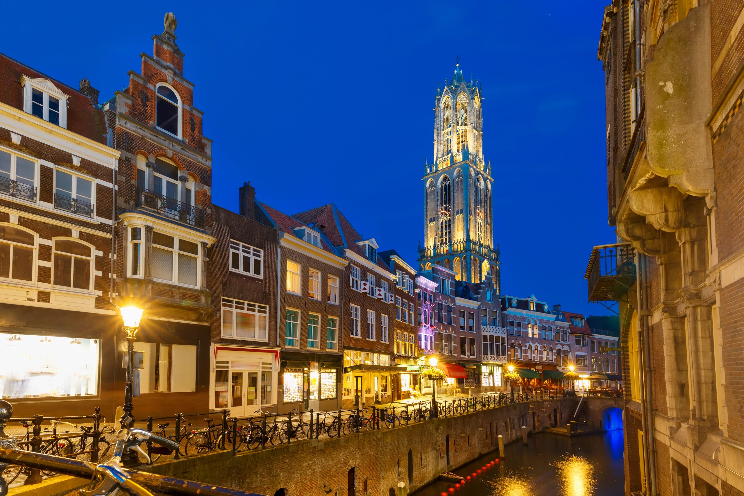 Dom Tower, bridge and canal Oudegracht in the night colorful illuminations in the blue hour, Utrecht, Netherlands